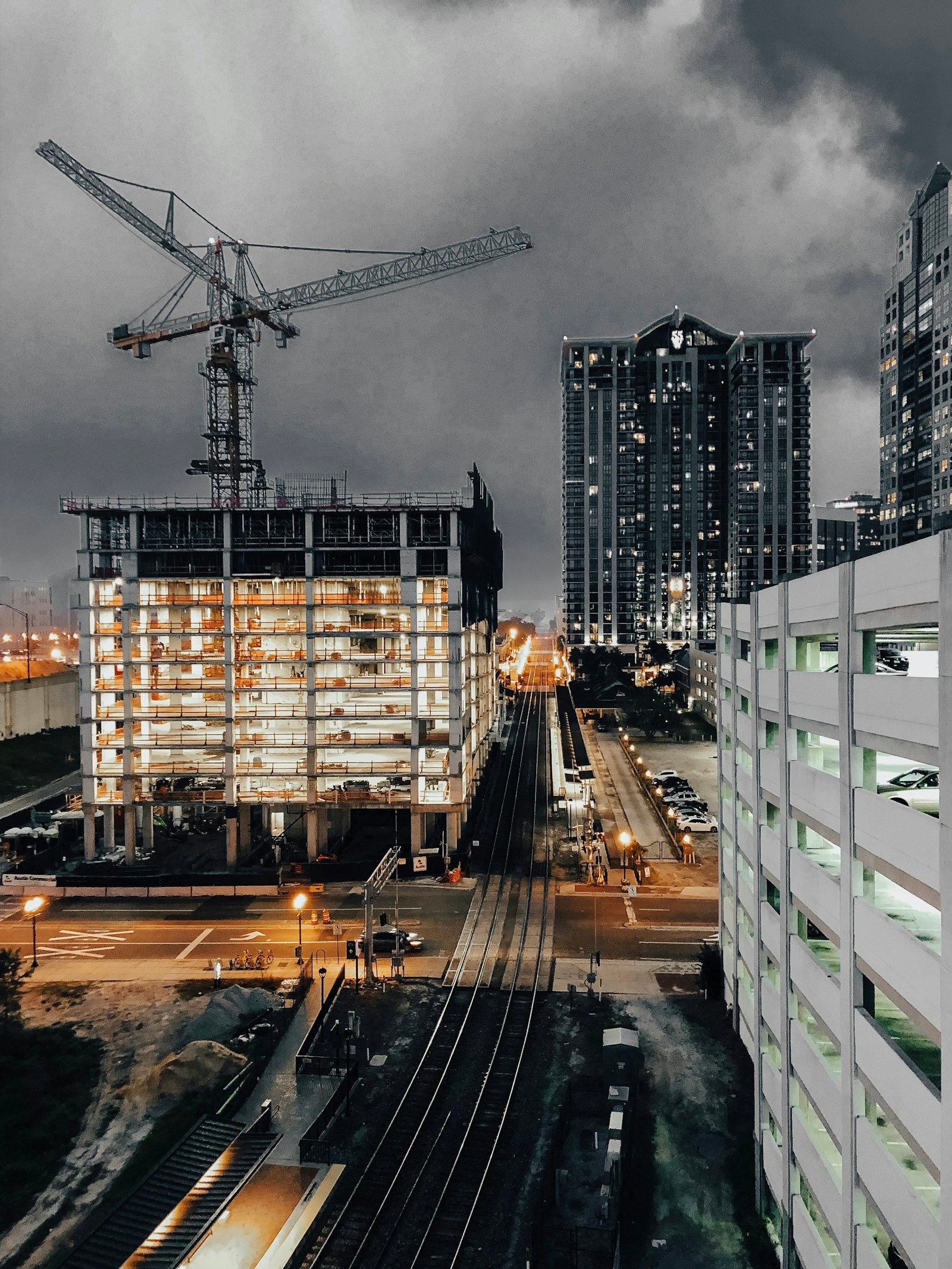 Commercial building under construction at dusk with site lighting