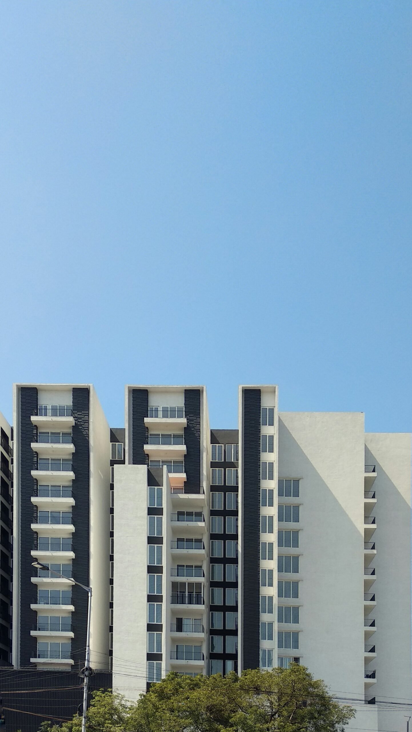 White multifamily residential building with balconies under a blue sky