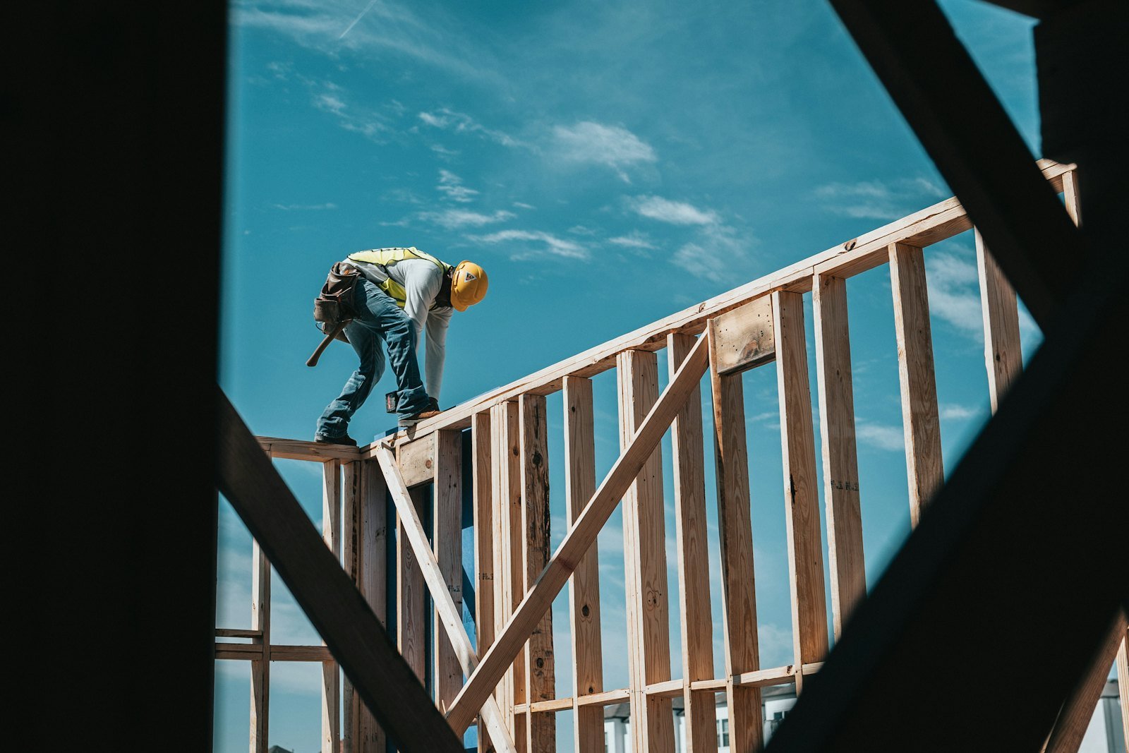 Carpenter framing the structure of a commercial building against a blue sky